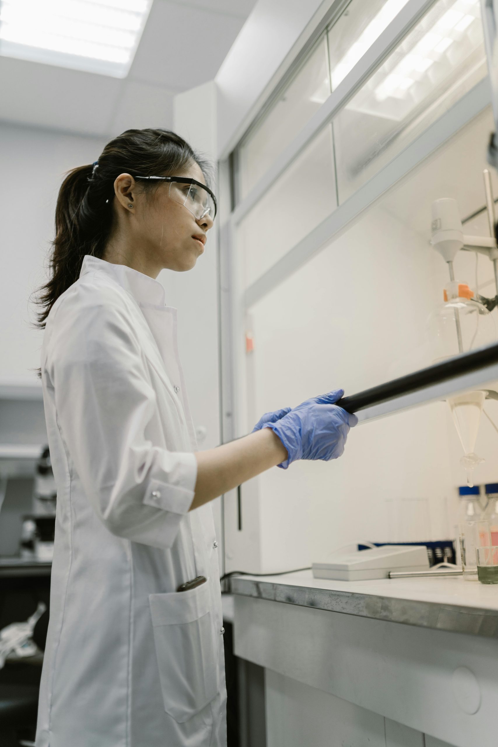 A female scientist performing an experiment in a laboratory, wearing safety gear.